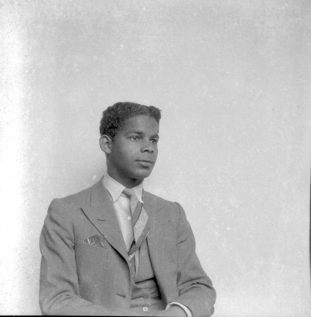 Studio portrait of Boy Ecury sitting and looking forward in a suit