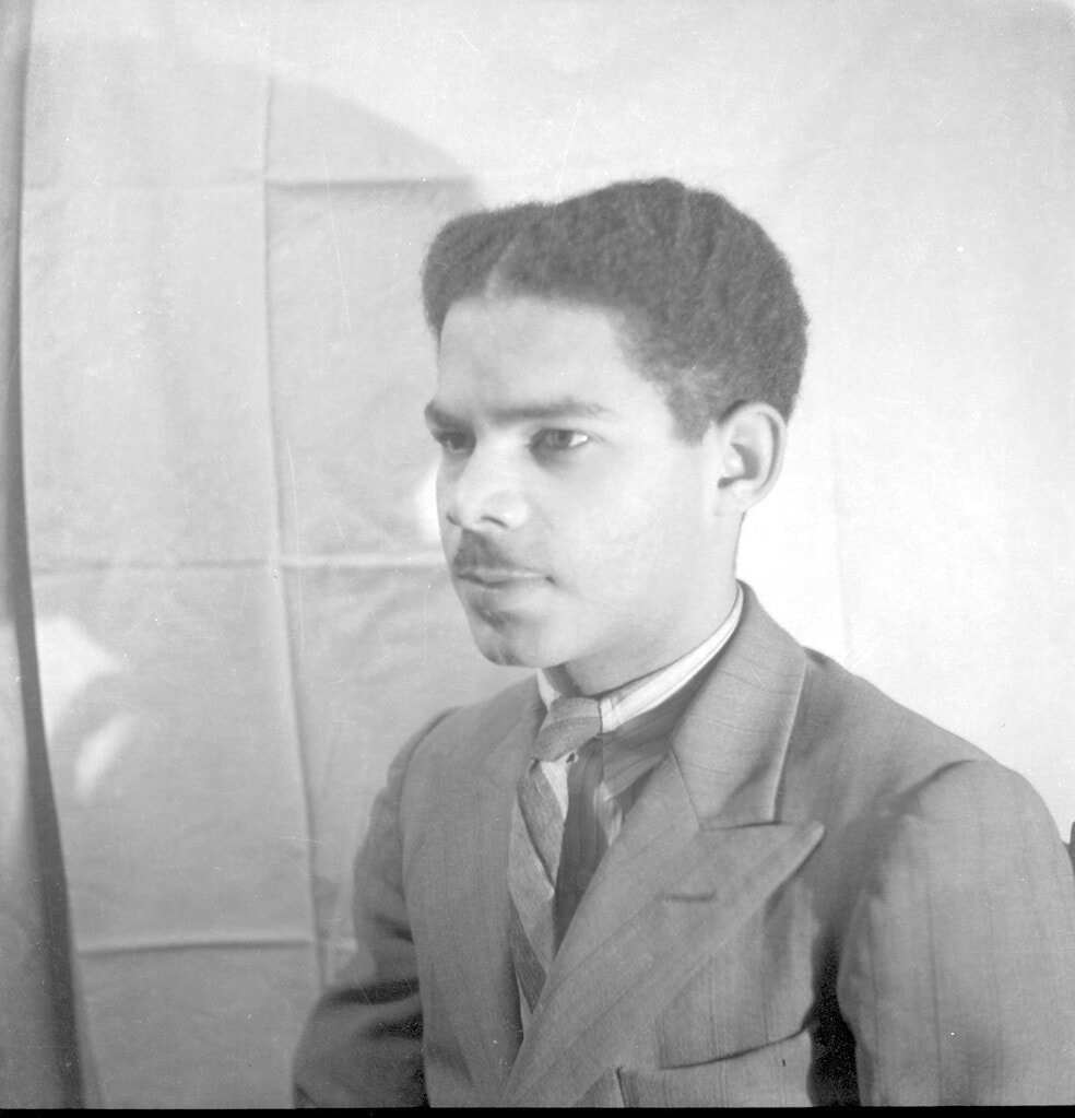 Studio portrait of Boy Ecury looking to the left, wearing a suit and tie
