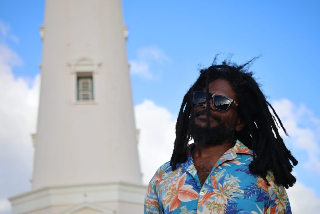 Tour guide Beach Lama standing in front of the California Lighthouse in Aruba on a clear sunny day.