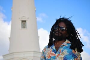 Tour guide Beach Lama standing in front of the California Lighthouse in Aruba on a clear sunny day.