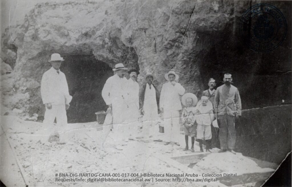 Historic photograph of miners and families at a gold mine entrance in Aruba.