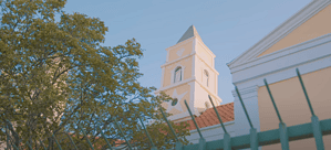 Close-up of the Protestant Church tower in Oranjestad Aruba, highlighting its yellow facade and colonial architecture.