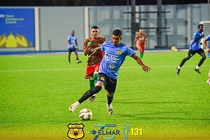 This image depicts young athletes participating in an energetic soccer game on a lush green field at Djis Pa Hari, highlighting youth sports, soccer skills, athletic competition, community engagement, and local football initiatives.