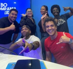 Vibrant group photo of Djis Pa Hari team celebrating, smiling, and making gestures against a blue backdrop with logo, showcasing fun, friendship, and music event atmosphere.