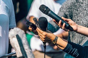 Microphone and voice recorder being held during an interview or press conference, capturing audio for media coverage or communication purposes.