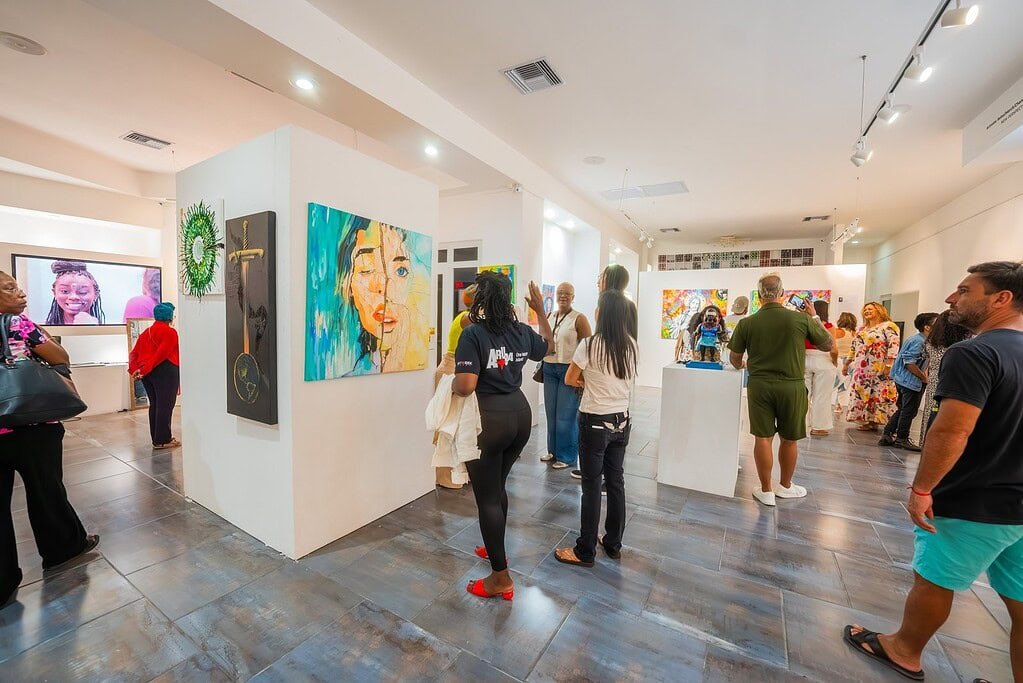 Visitors exploring contemporary art at Djis Pa Hari art exhibition in Aruba, showcasing vibrant paintings and cultural artworks inspired by Aruba’s artistic impact.