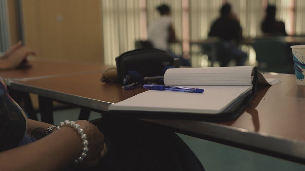 People in a meeting discussing job opportunities, with notebooks and pens on the table, in a professional setting.